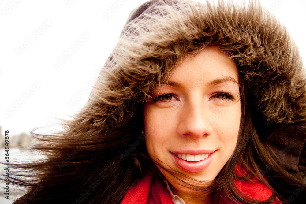 A woman with a warm furry jacket, and red scarf smiling. A woman with a warm furry jacket, and red scarf smiling.