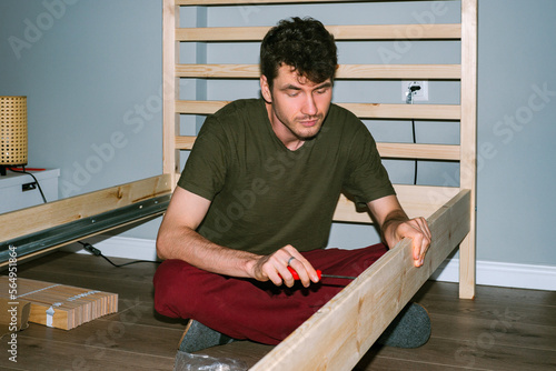  Man enthusiastically assembles a wooden bed 