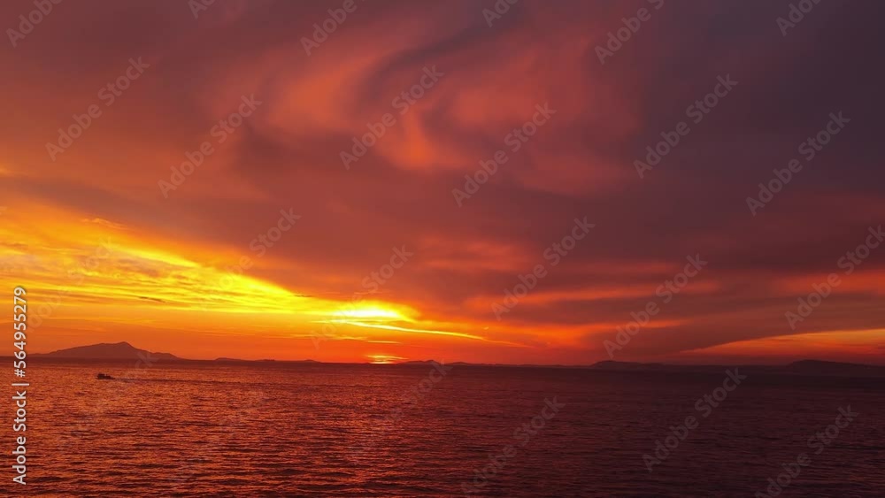 Majestic sunset or sunrise landscape. Beautiful cloudscape over the sea. Amazing light, pink and red sunset. Boats moving past. Red purple orange blue pink sunset sky cloud. Red sky, yellow sun. 