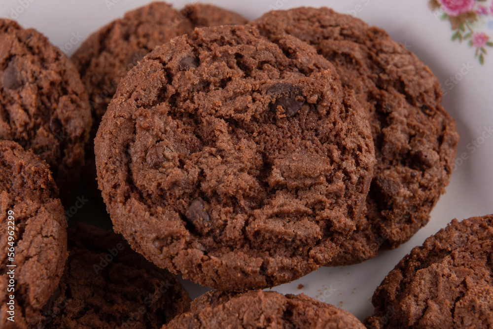 Tasty chocolate chip cookies on white plate on wooden background. Selective focus. Tasty chocolate chip cookies on white plate on wooden background. Selective focus.