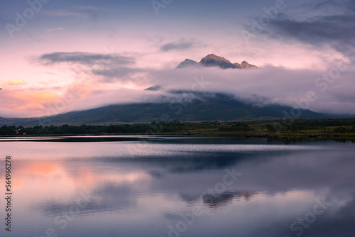 Spectacular reflection of the mountains on a lake with mist under the midnight sun, fairy tale atmosphere in the Vesteralen Islands, Norway