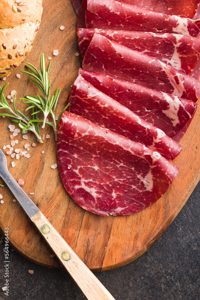 Smoked bresaola. Italian appetizer. Dried beef meat on cutting board. Top view. Smoked bresaola. Italian appetizer. Dried beef meat on cutting board. Top view.