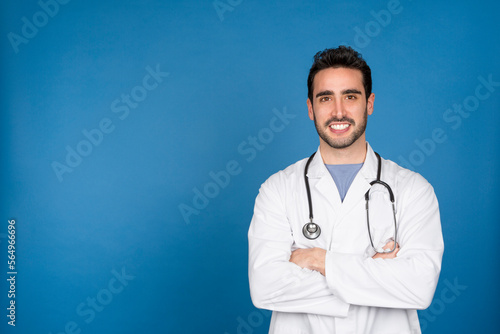 Caucasian young doctor smiling at the camera with arms crossed