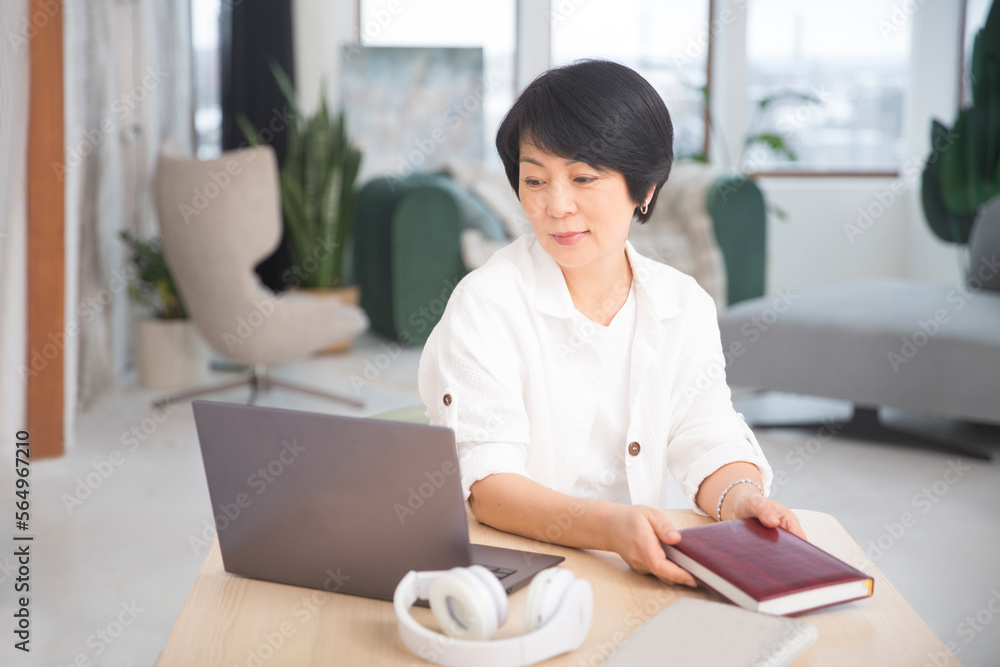 The adorable Asian businesswoman in headphones communicates online sits on a laptop in the office. healthy lifestyle. work from home The adorable Asian businesswoman in headphones communicates online sits on a laptop in the office. healthy lifestyle. work from home