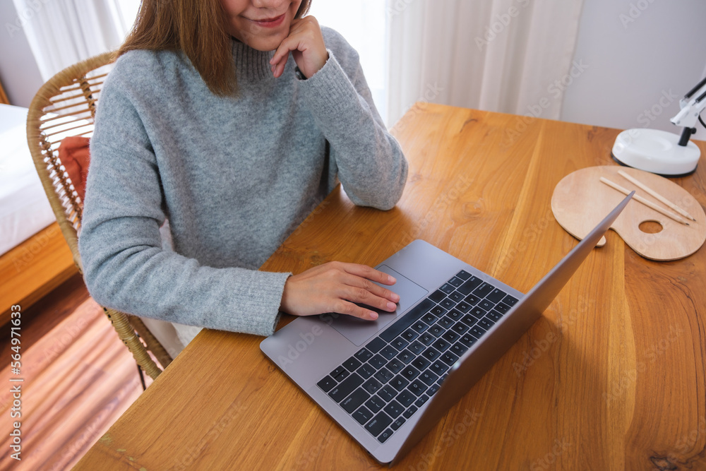 Closeup image of a young woman with chin resting, working on laptop computer at home Closeup image of a young woman with chin resting, working on laptop computer at home