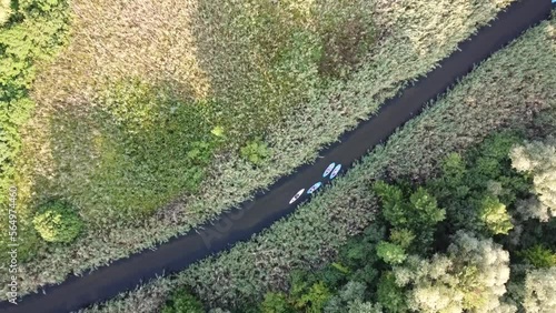 Four kayaks sail on a narrow river among nature and forest. Top view. High quality FullHD footage