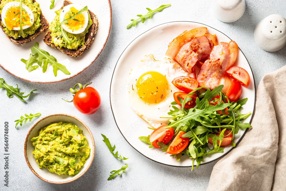 Healthy breakfast or lunch. Beacon, eggs, toast with avocado and fresh salad. Top view on white. Healthy breakfast or lunch. Beacon, eggs, toast with avocado and fresh salad. Top view on white.