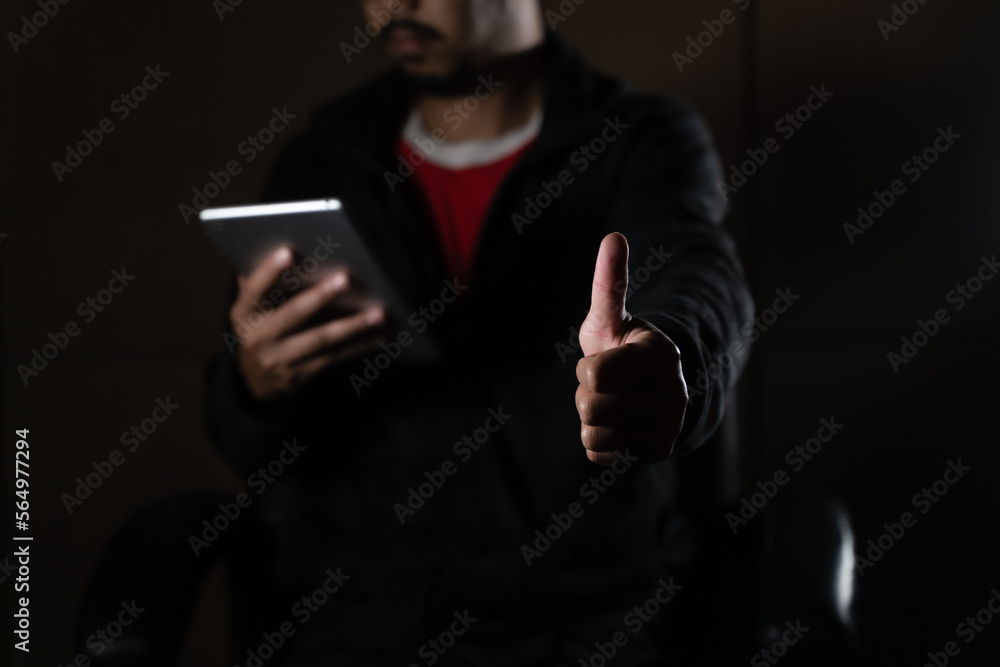 Cheerful bearded man in black long sleeve shirt using digital tablet in Dark room. hand holding tablet. Cheerful bearded man in black long sleeve shirt using digital tablet in Dark room. hand holding tablet.