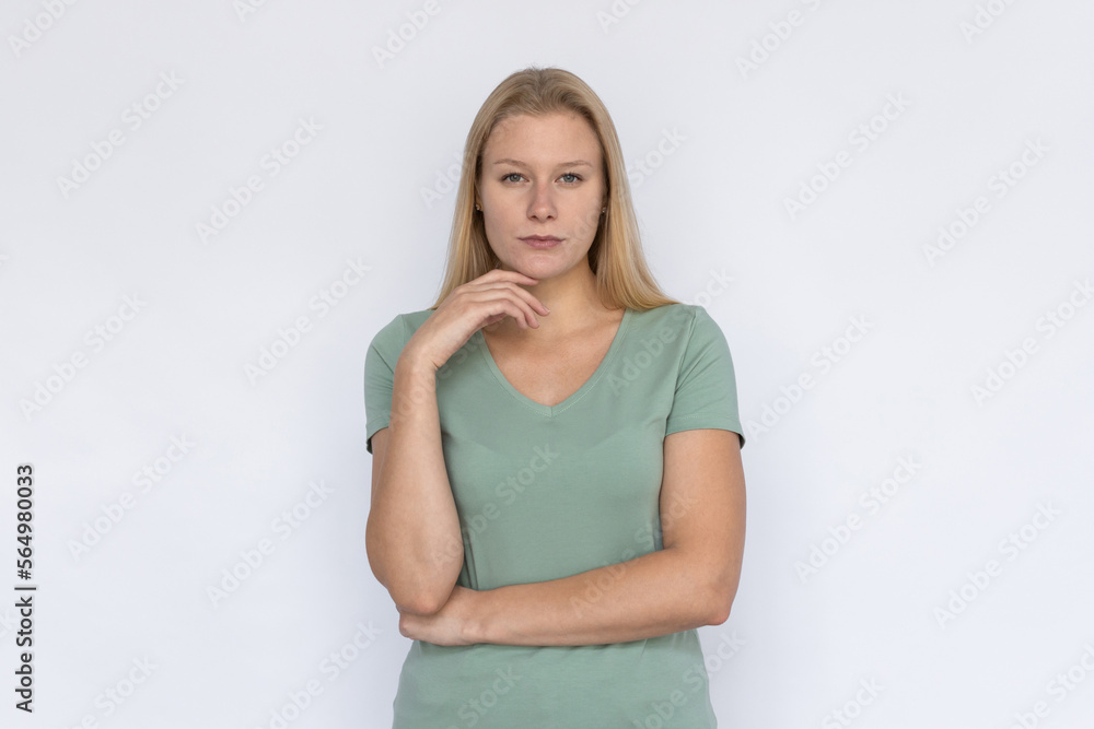Confident woman looking at camera. Young female model standing with hand at face expressing confidence. Portrait, studio shot, confidence concept Confident woman looking at camera. Young female model standing with hand at face expressing confidence. Portrait, studio shot, confidence concept