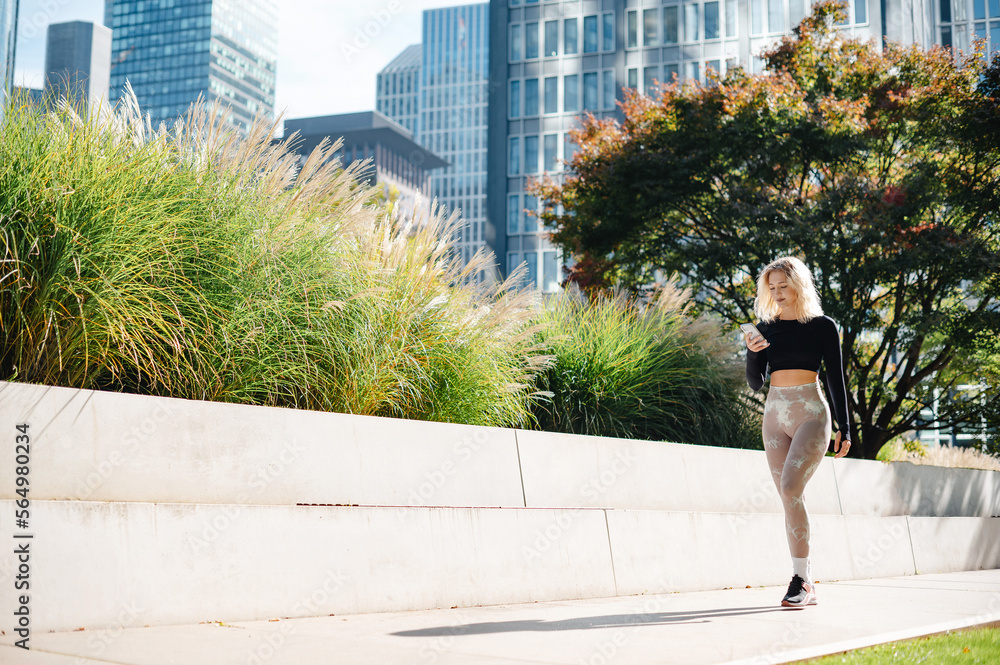 Fototapeta premium Fitness runner using mobile app while tracking progress outdoors