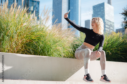 Fototapeta Naklejka Na Ścianę i Meble -  Fitness lady making selfie using mobile outdoors