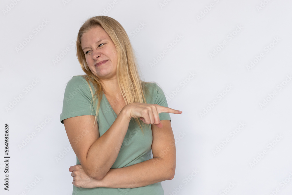 Disapproving woman pointing aside. Young female model disgusted by something. Portrait, studio shot, disapproval, disgust concept Disapproving woman pointing aside. Young female model disgusted by something. Portrait, studio shot, disapproval, disgust concept