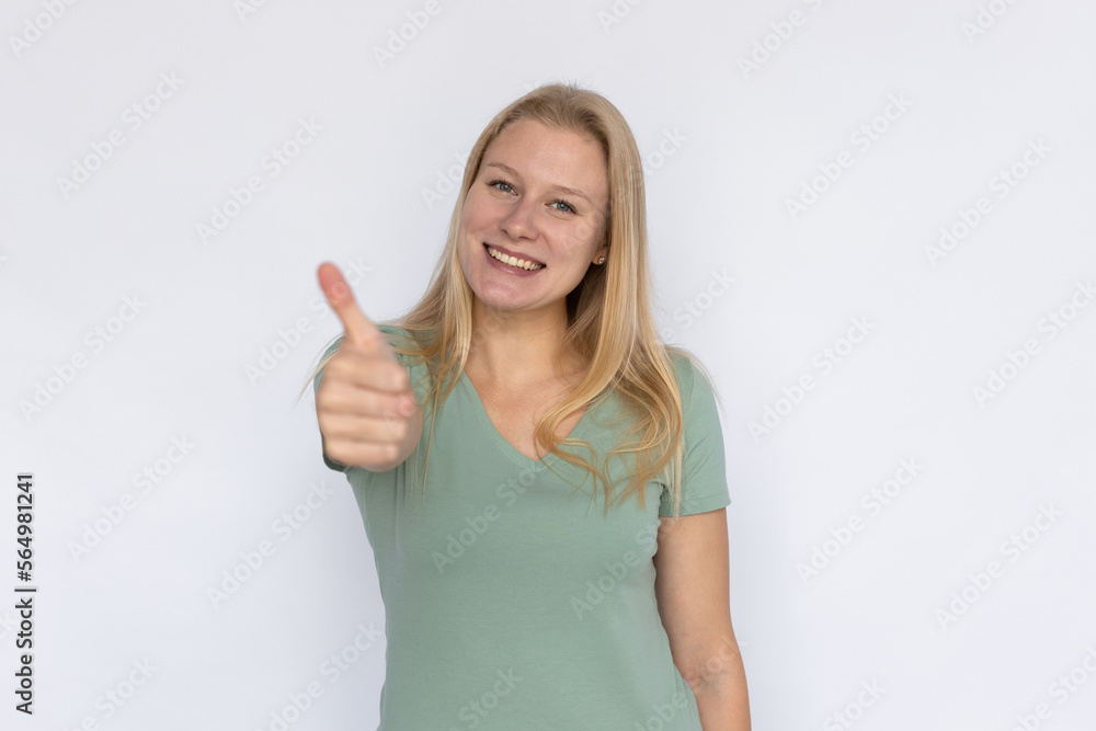 Positive woman showing thumbs up. Young female model expressing positive opinion with gesture. Portrait, studio shot, quality, support concept Positive woman showing thumbs up. Young female model expressing positive opinion with gesture. Portrait, studio shot, quality, support concept