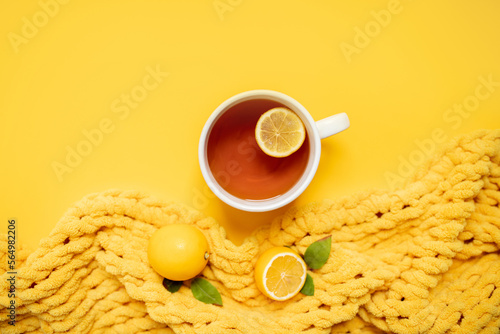 black lemon tea in a large cup on a yellow background with a yellow blanket and lemons. copy space. top view. flat lay. photo
