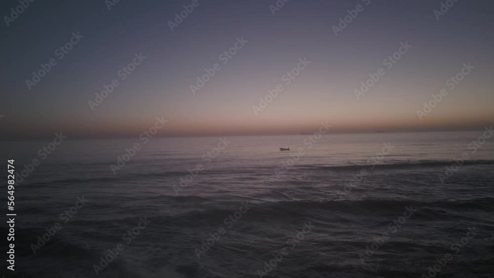 Stunning view of boat over huge ocean with orange sky, boats illuminated, Portugal Stunning view of boat over huge ocean with orange sky, boats illuminated, Portugal