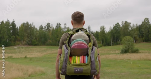 Disc golfer walking on the course with back bag full of discs photo