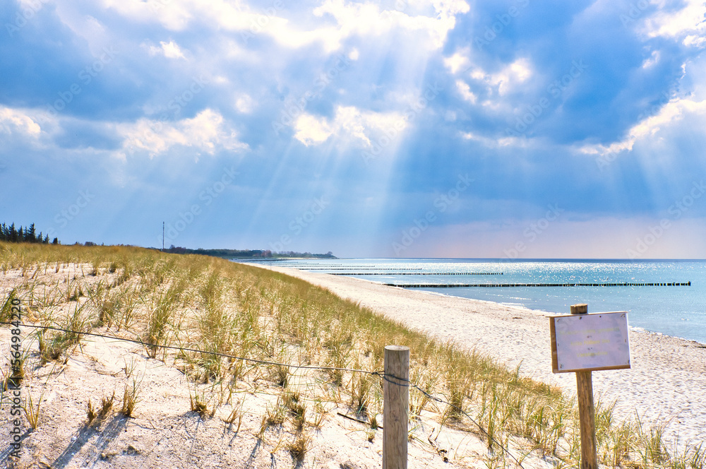 Sun rays shining through thick clouds on the beach of the Baltic Sea.Sign beach crossing
