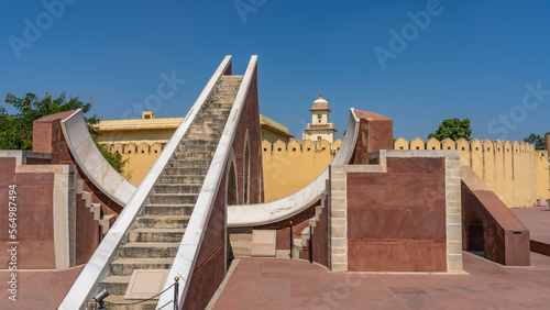 A sundial in the ancient famous observatory of Jantar Mantar. Divisions are applied on the curved white marble surface to determine the exact time. Stairs in the center. Blue sky. India Jaipur photo