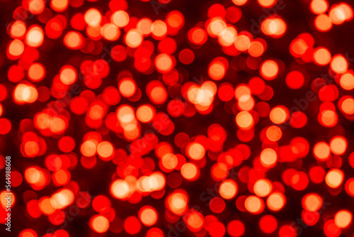 Defocused red bokeh confetti circles on black background with depth effect. Abstract backdrop with red circles