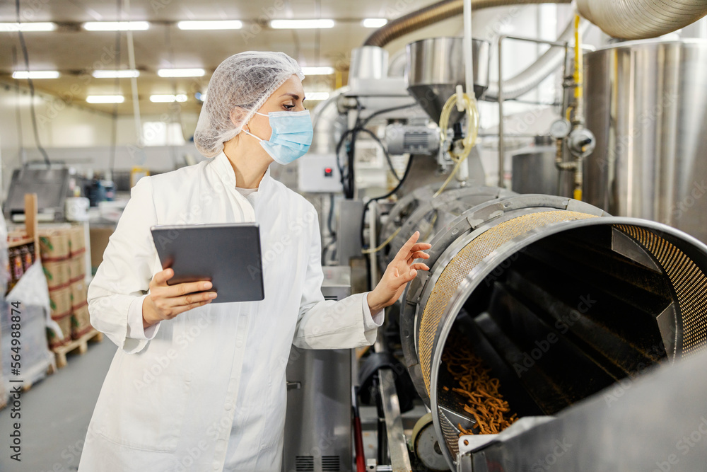 A food factory supervisor is rating quality of salty sticks in machine. A food factory supervisor is rating quality of salty sticks in machine.