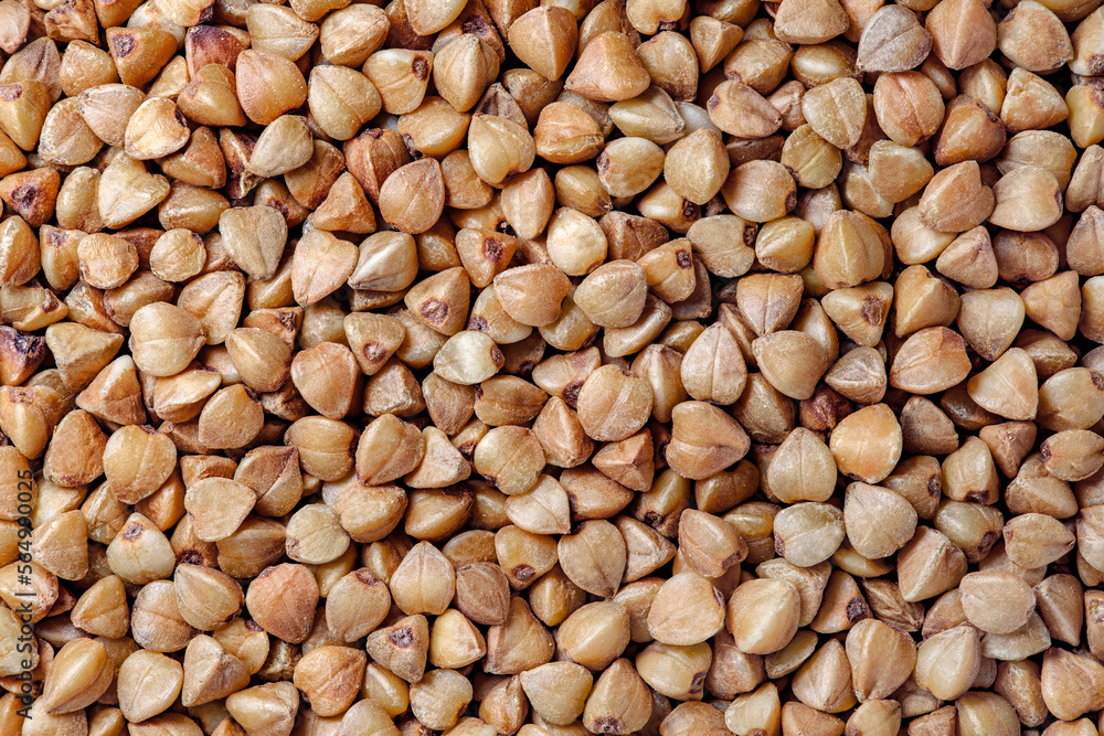 Buckwheat groats raw, bunch in bulk, close-up macro view, background wallpaper, uniform texture pattern Buckwheat groats raw, bunch in bulk, close-up macro view, background wallpaper, uniform texture pattern