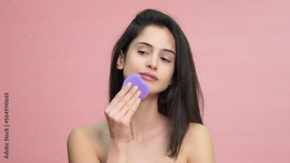 Smiling woman cleaning her skin with sponge Smiling woman cleaning her skin with sponge