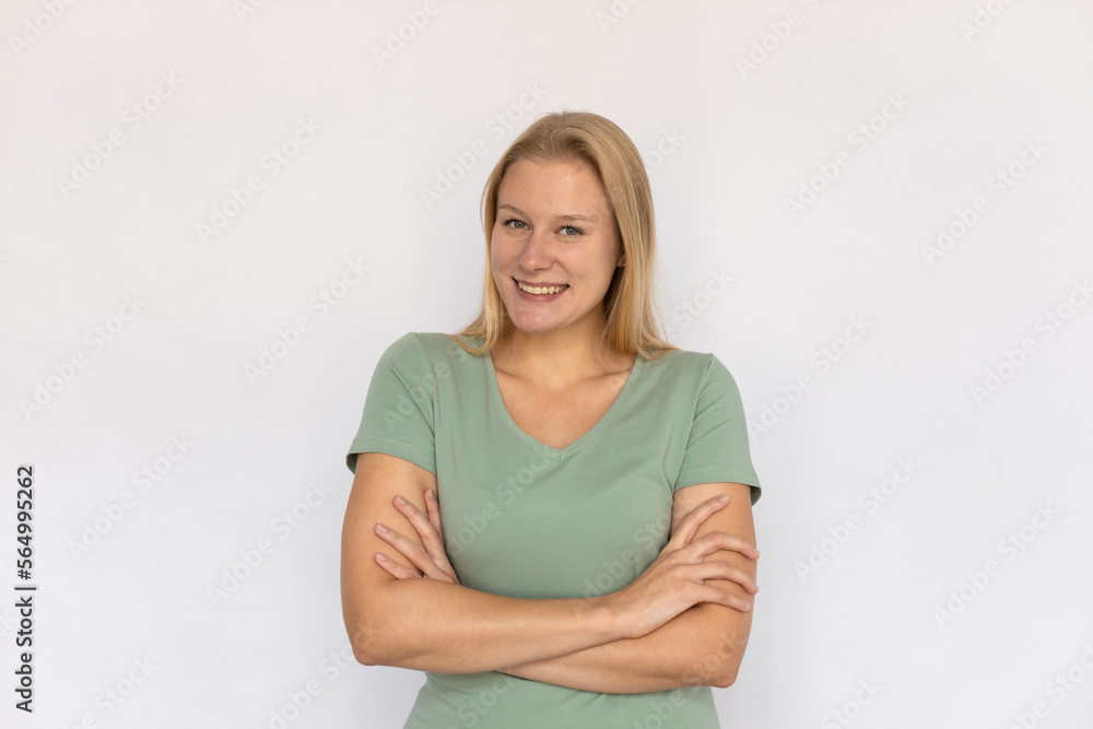 Excited young woman crossing arms. Portrait of happy Caucasian female model with fair hair in green T-shirt looking at camera, smiling, proud of herself. Happiness, success concept Excited young woman crossing arms. Portrait of happy Caucasian female model with fair hair in green T-shirt looking at camera, smiling, proud of herself. Happiness, success concept