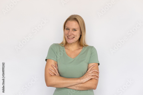 Excited young woman crossing arms. Portrait of happy Caucasian female model with fair hair in green T-shirt looking at camera, smiling, proud of herself. Happiness, success concept