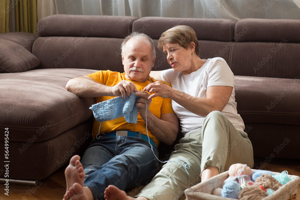 Fototapeta premium spend free time do favourite hobby. life concept. elderly couple With Wool Knitting sitting on the sofa at home. Happy Valentine's Day