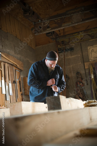 A timber framer cleans out a mortise joint with a mortise chisel. photo