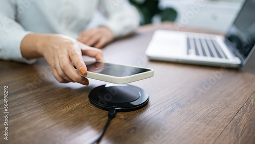 Fotografia Charging mobile phone battery with wireless charging device in the table