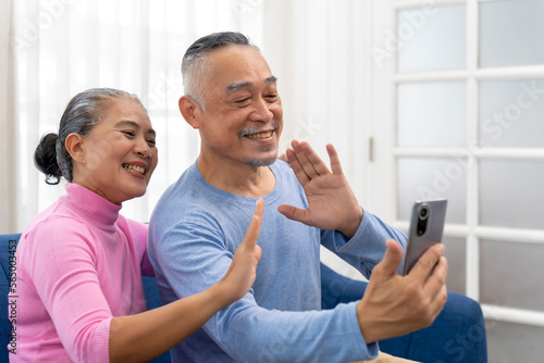 Senior couple use smartphone to video call in living room