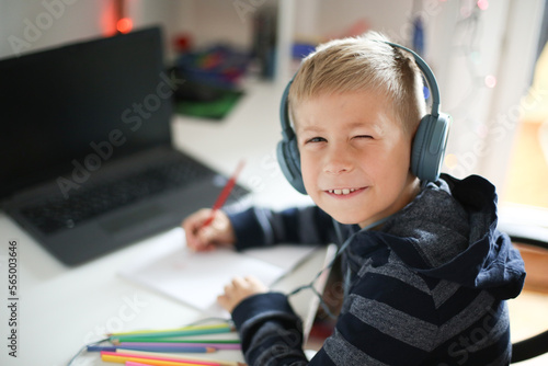 Portrait of a boy with laptop and headset at home or office
