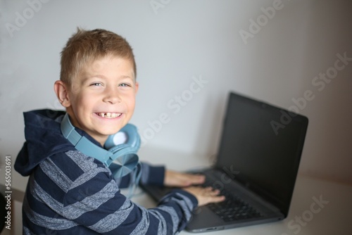 Portrait of a boy with laptop and headset at home or office