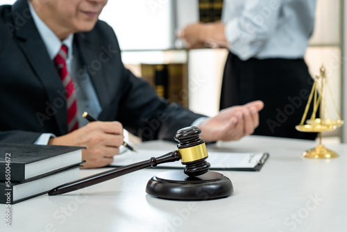 Male lawyer consulting and discussion to businesswoman client at law firm in office, Judge gavel with scales of justice