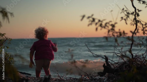 Silhouette Shot of Little Boy Throwing Rocks into the Water at the Beach During Sunset