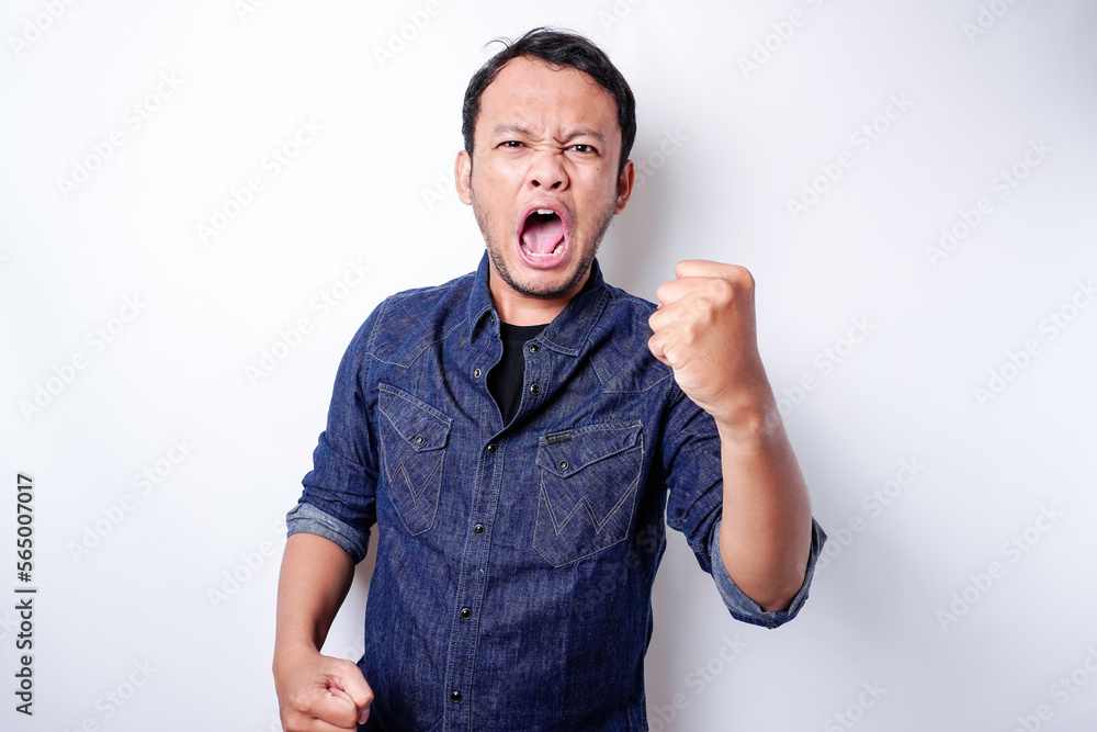 Fototapeta premium The angry and mad face of Asian man in blue shirt isolated white background.