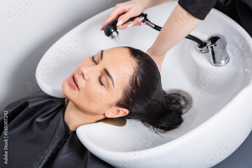professional hairdresser washing hair of young woman in beauty salonю Beautiful young woman with long black hair in a beauty salon.
