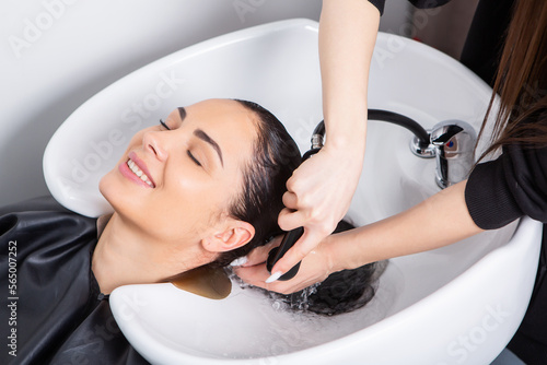 professional hairdresser washing hair of young woman in beauty salonю Beautiful young woman with long black hair in a beauty salon.