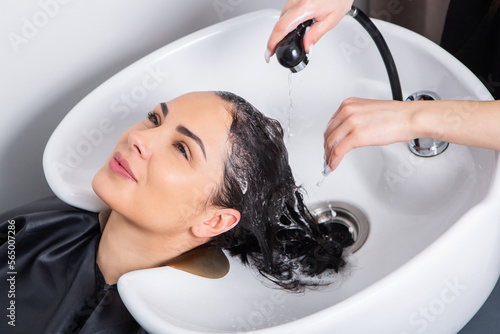 professional hairdresser washing hair of young woman in beauty salonю Beautiful young woman with long black hair in a beauty salon.