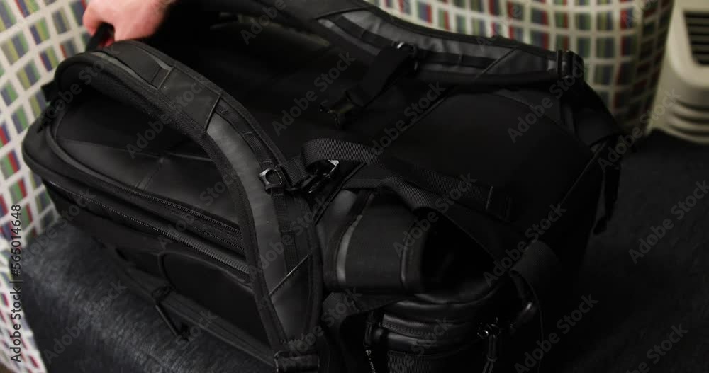 White hand reaching into scene opening a camera gear bag and grabbing a white telephoto lens White hand reaching into scene opening a camera gear bag and grabbing a white telephoto lens