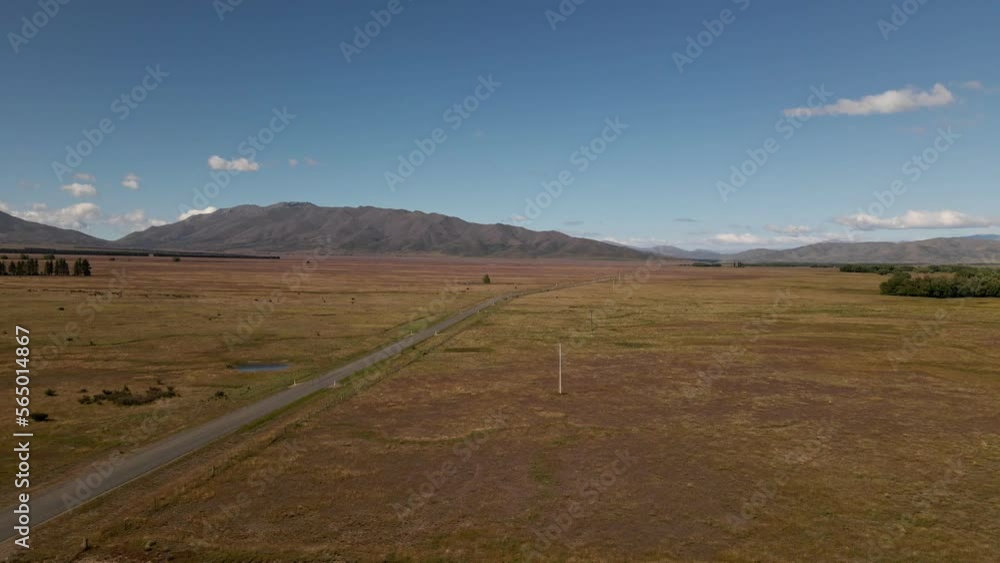Aerial view of empty desert highway leading through dry plains in sunshine