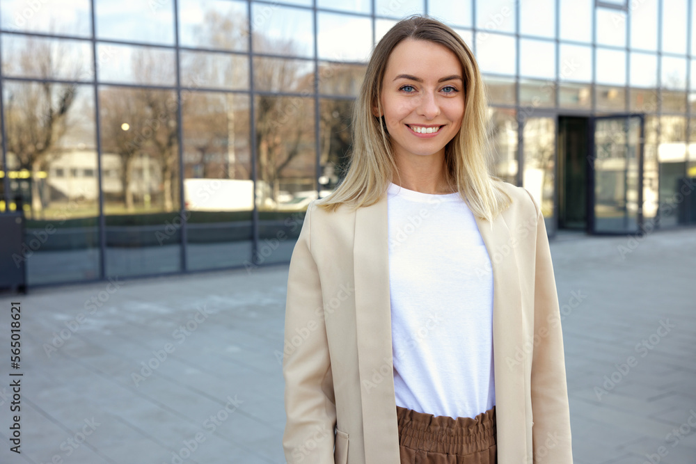 Fototapeta premium Portrait of the beautiful smiling businesswoman in formal outfit standing near the business centre looking at the camera. People and business concept.