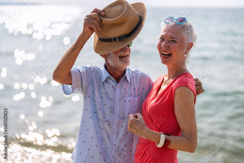 Couple of old mature people dancing together on the sand at the beach enjoying and living the moment