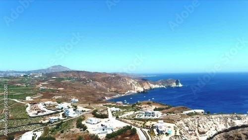 Aerial 4K Blue Sea and Sky Top Flyover View of Village of Akra Mavro Vouno with sailboats docked in Santorini Greece photo