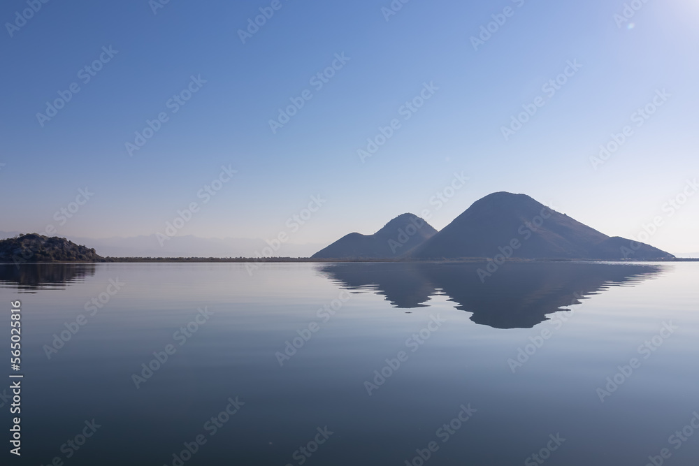 Scenic view of Lake Skadar National Park in autumn near Virpazar, Bar, Montenegro, Balkans, Europe. Hills striking out with Dinaric Alps in back, Albania. Stunning landscape water reflection in nature