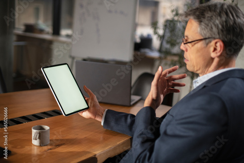 Portrait of businessman in office. Man using digital tablet. Businessman having video call.