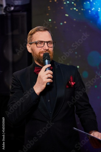 Portrait of a smart and handsome intelligent business coach in a stylish suit and glasses speaking into a microphone with a confident wise expression