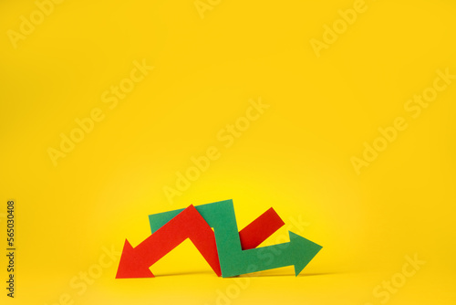 Indecision in the stock or crypto market. Red and green arrows intertwined on yellow background. Economic growth or global recession. photo