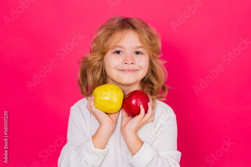 Kid with apple in studio. Studio portrait of cute child hold apple isolated on red background.